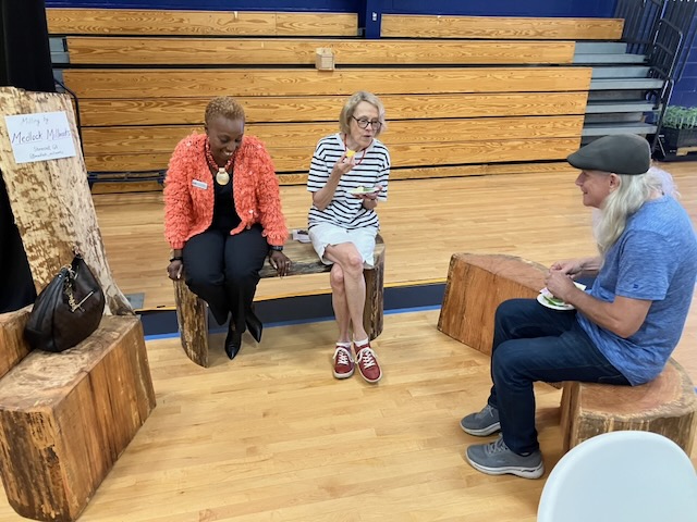 Members sitting on benches inside near to each other.